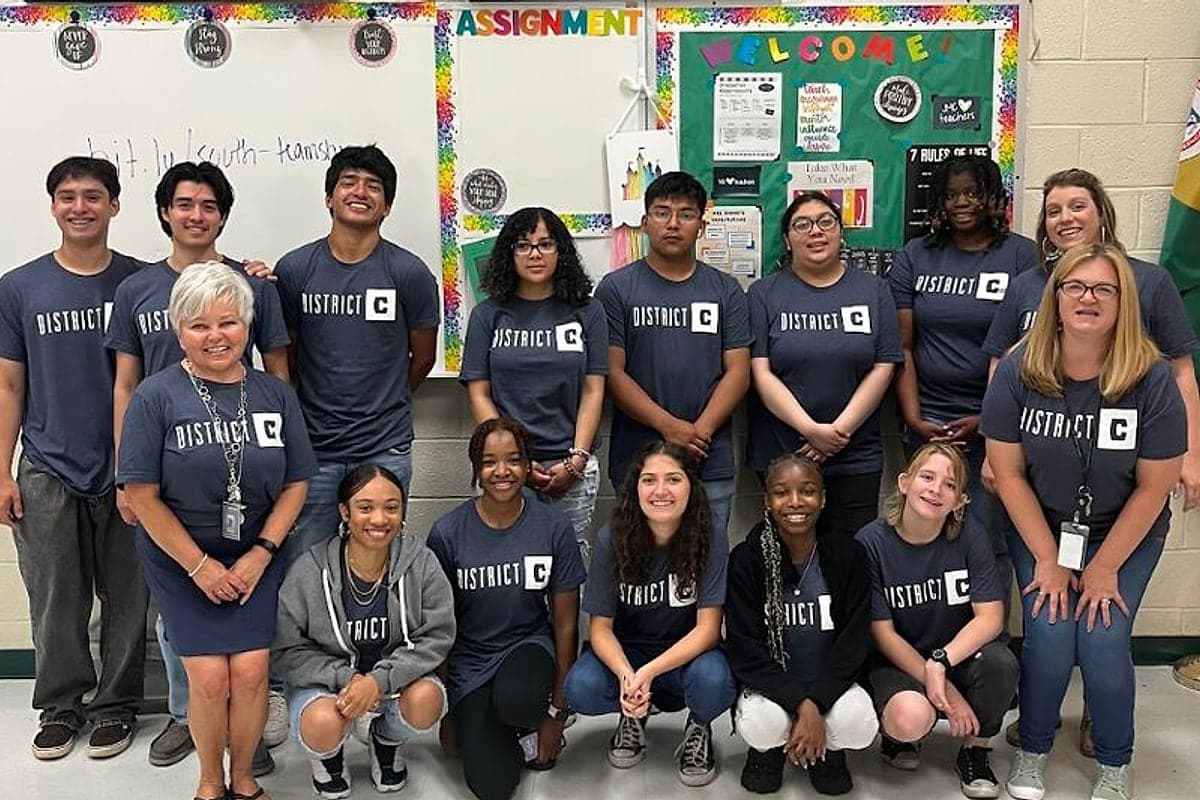 District C students and teachers in branded shirts gathered in a classroom